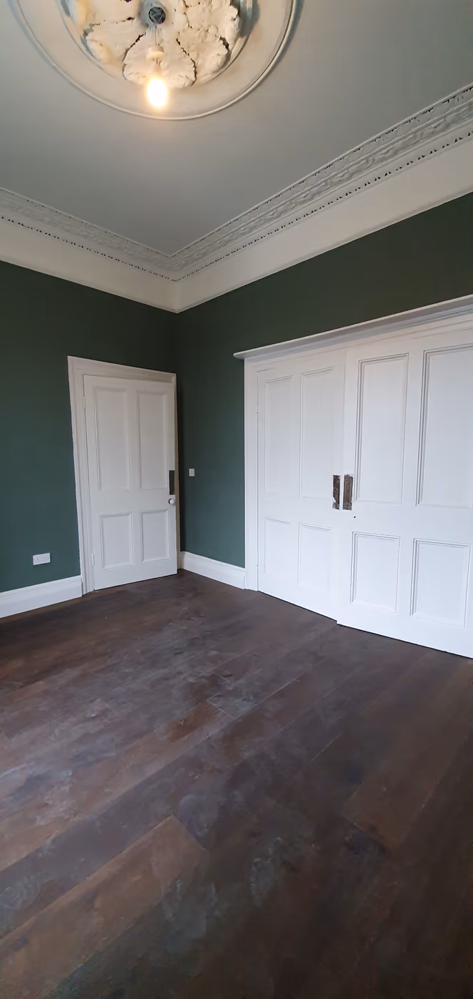 Built-in fitted wardrobes painted white against a green wall in a Dublin bedroom